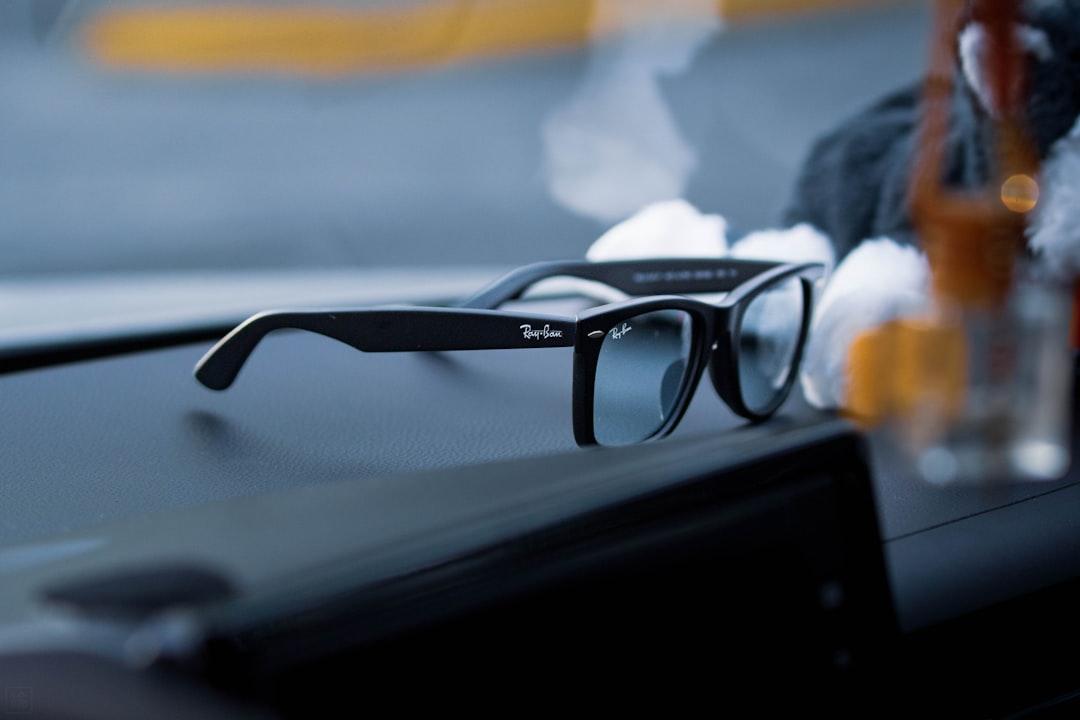 Person wearing black wayfarer sunglasses in city light